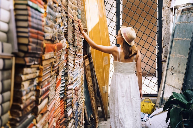 Jonge vrouw die boek in oude tweedehands boekhandel libreria acqua alta in venetië italië kiest