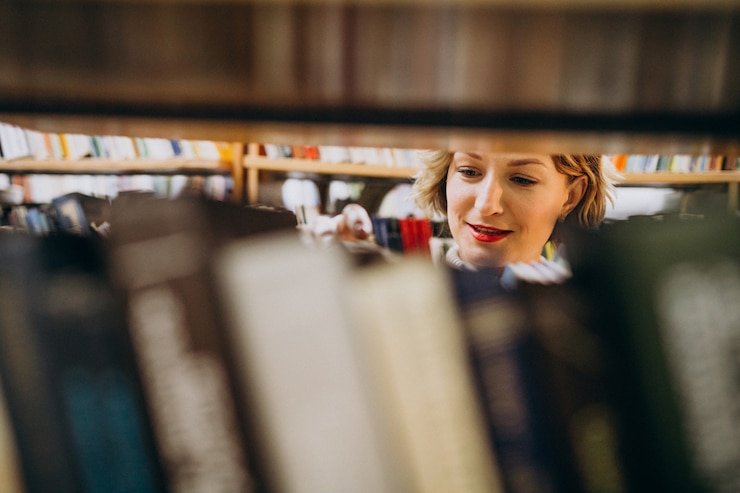 Gratis Foto jonge vrouw die boek kiest bij de bibliotheek