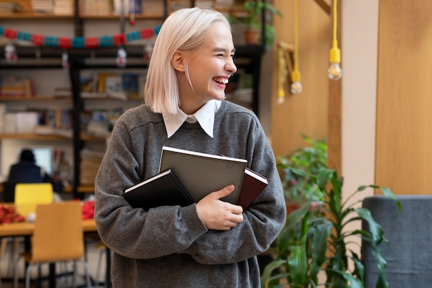 Jonge vrouw die boeken uit een bibliotheek haalt om te studeren