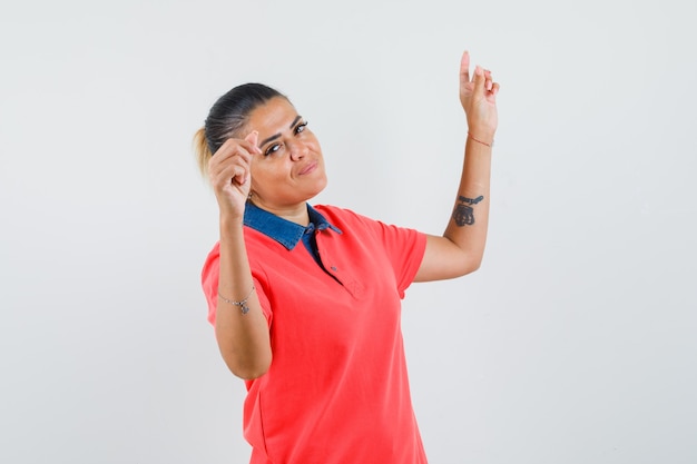 Jonge vrouw die dansgebaar in rood t-shirt toont en mooi kijkt. vooraanzicht.