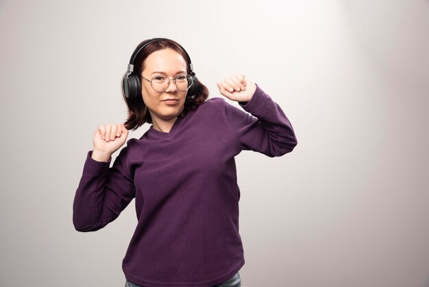 Jonge vrouw die danst en muziek luistert in een koptelefoon op een wit. hoge kwaliteit foto