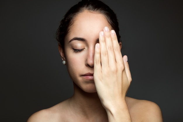 Gratis foto jonge vrouw die de helft van haar gezicht met een hand bedekt.