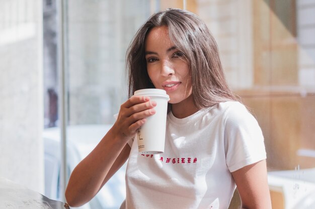 Jonge vrouw die de koffie in koffie drinkt