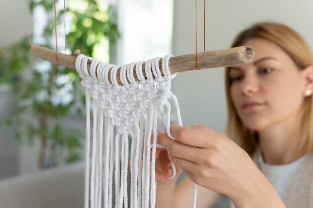 Jonge vrouw die de macramé-techniek gebruikt