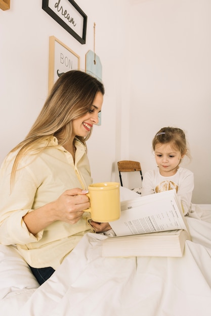 Gratis foto jonge vrouw die dichtbij dochter leest