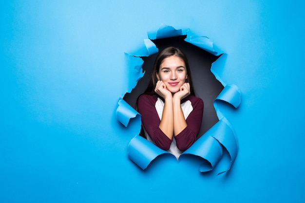 Jonge vrouw die door blauw gat in document muur kijkt.