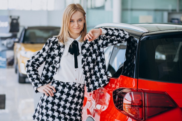 Jonge vrouw die een auto in een autotoonzaal koopt