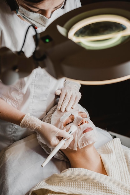 Jonge vrouw die een behandeling van het huidmasker krijgt