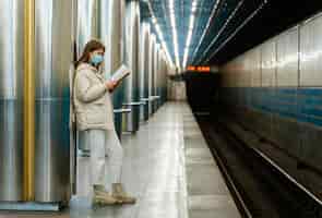 Gratis foto jonge vrouw die een boek in een metrostation leest