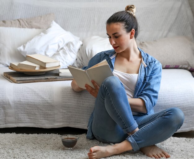 Jonge vrouw die een boek leest in een gezellige kamer