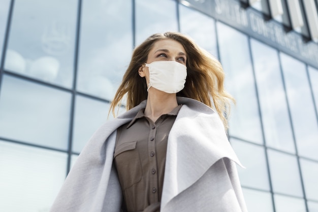 Jonge vrouw die een gezichtsmasker draagt met een modern gebouw