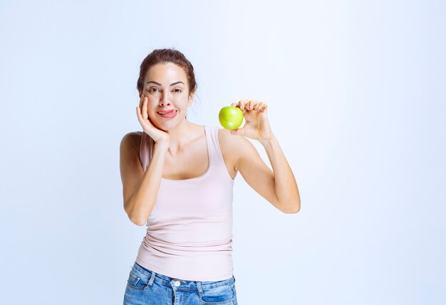 Jonge vrouw die een groene appel vasthoudt en denkt