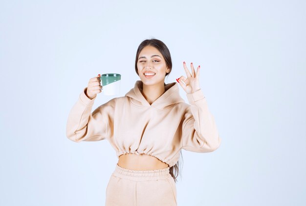 Jonge vrouw die een groene mok houdt en haar tevredenheid toont