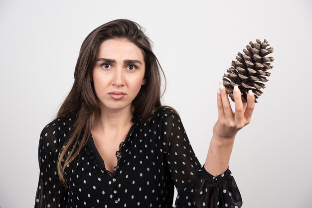 Jonge vrouw die een grote dennenappel houdt