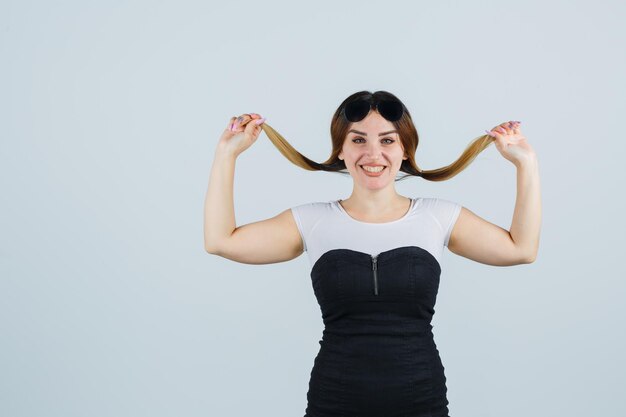 Jonge vrouw die een haarlok vasthoudt en er gelukkig uitziet