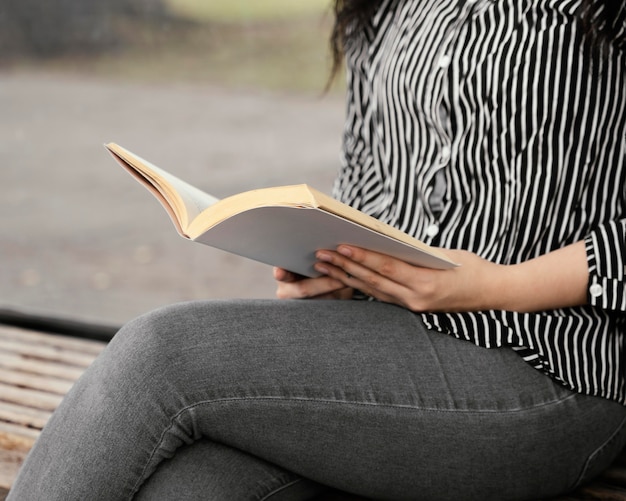 Jonge vrouw die een interessant boek buitenshuis leest