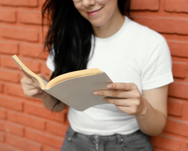 Gratis foto jonge vrouw die een interessant boek buitenshuis leest