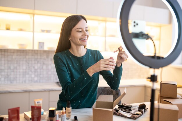 Jonge vrouw die een monster van nieuwe verstevigende crème op haar hand aanbrengt