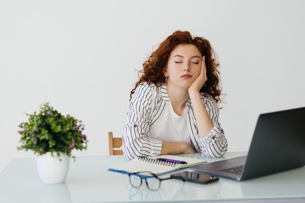 Jonge vrouw die een pauze neemt en ontspant met haar handen achter haar hoofd en op een bureaustoel zit