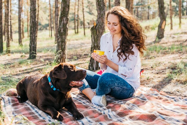 Jonge vrouw die een picknick met haar hond doet