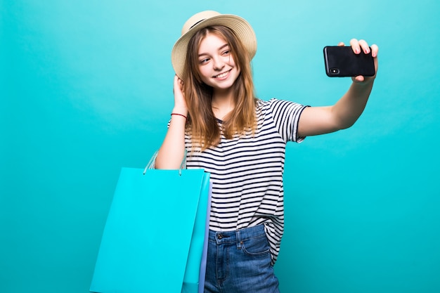 Jonge vrouw die een selfie op uw smartphone zitten met gekleurde tassen om te winkelen