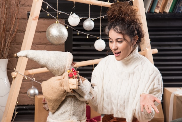 Jonge vrouw die een speelgoed van de Kerstman vasthoudt