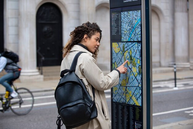 Jonge vrouw die een stationskaart in de stad raadpleegt