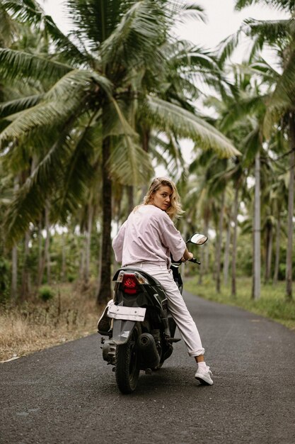 jonge vrouw die een tropisch leven op een bromfiets bestuurt