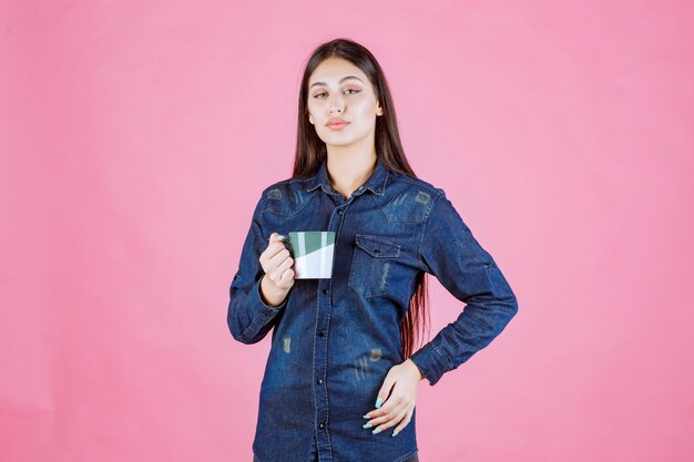 Jonge vrouw die een witgroene koffiemok houdt en ruikt