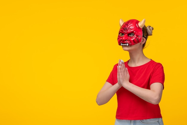 Jonge vrouw die eng duivelsmasker draagt dat gele achtergrond halloween lelijk smeekt