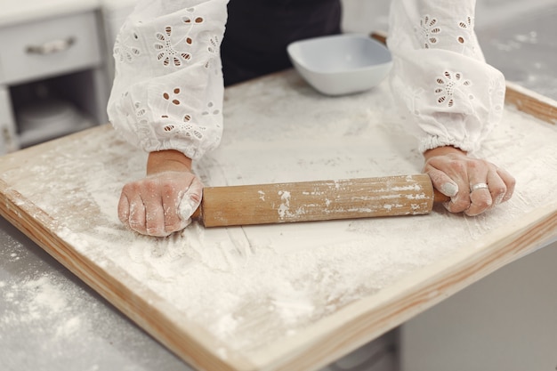 Gratis foto jonge vrouw die gevormde koekjes voor kerstmis maakt. woonkamer versierd met kerstversieringen op de achtergrond. vrouw in een schort.