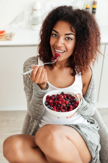 Jonge vrouw die gezond voedsel in keuken eet