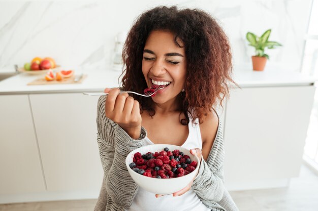 Jonge vrouw die gezond voedsel in keuken eet