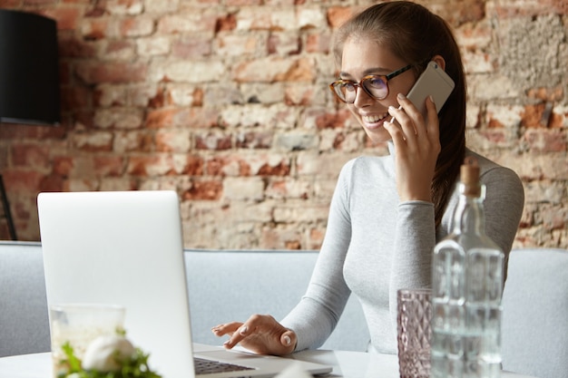 Gratis foto jonge vrouw die grijze coltrui en oogglazen draagt