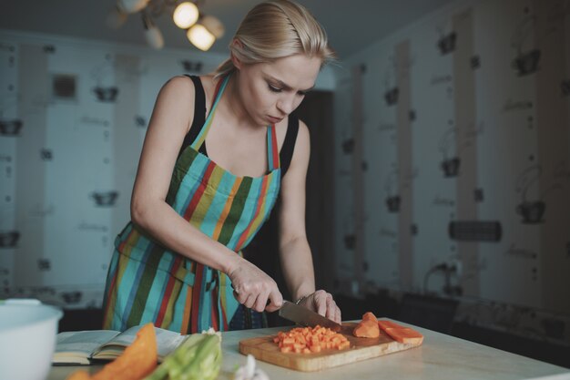 Jonge vrouw die groenten snijdt