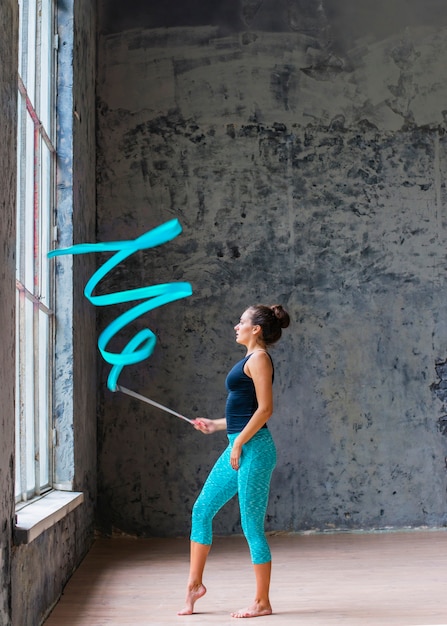Jonge vrouw die gymnastiek- dans met blauw lint doet