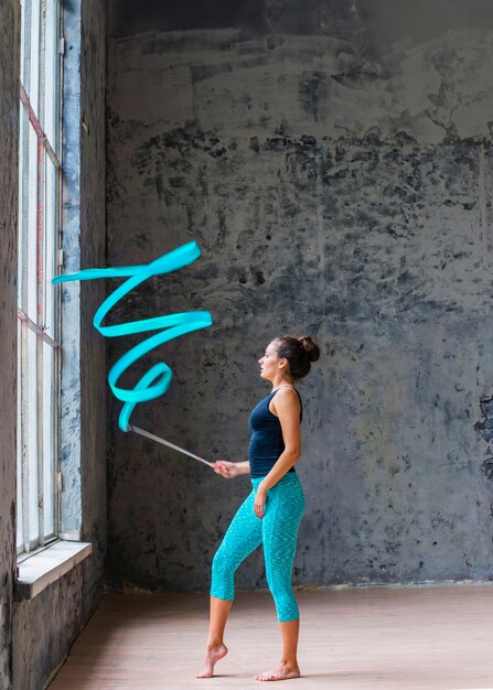 Jonge vrouw die gymnastiek- dans met blauw lint doet