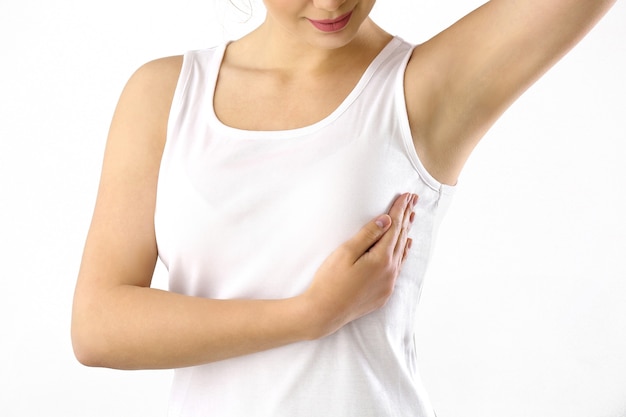 Jonge vrouw die haar borst controleert op witte achtergrond. kanker bewustzijn concept Premium Foto