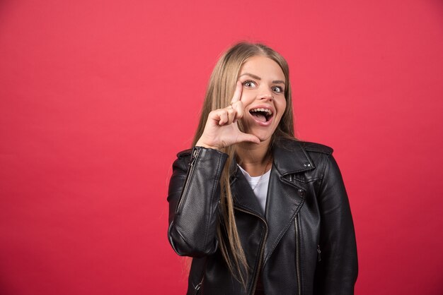 Jonge vrouw die haar gezicht op een rode muur aanraakt