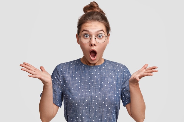 Gratis foto jonge vrouw die haar haar in een broodje en een polka dot blouse draagt