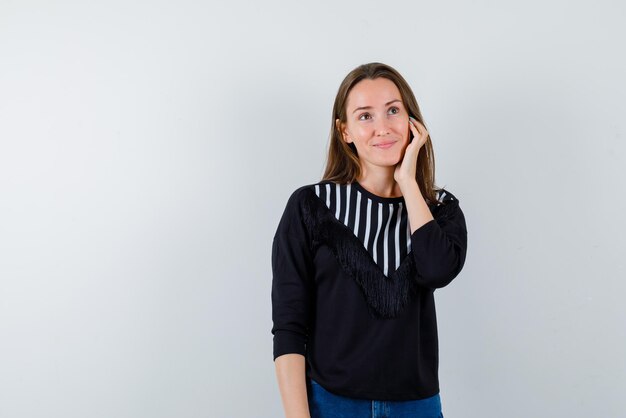 Jonge vrouw die haar handen op haar gezicht houdt op witte achtergrond