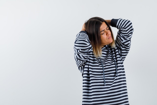 Jonge vrouw die haar hoofd met handen op witte achtergrond houdt