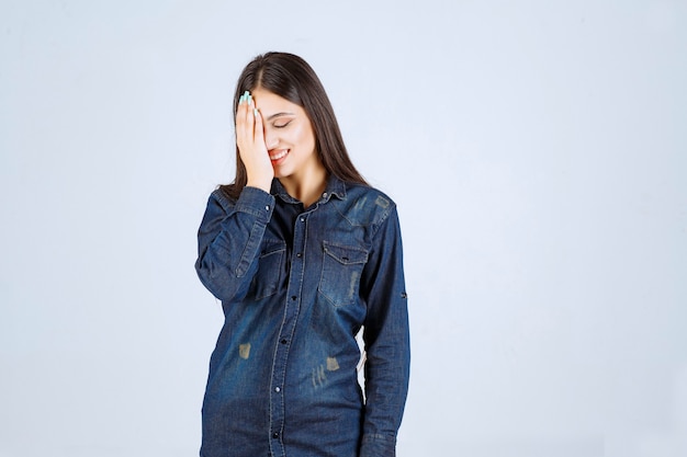 Jonge vrouw die haar ogen of een deel van het gezicht sluit en door haar vingers kijkt