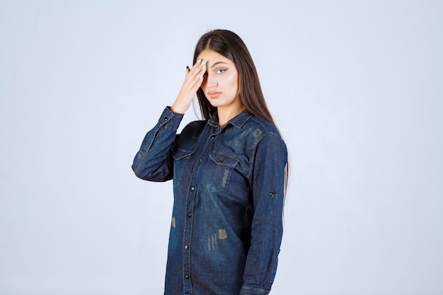 Jonge vrouw die haar ogen of een deel van het gezicht sluit en door haar vingers kijkt