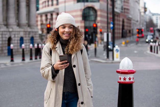 Jonge vrouw die haar smartphone in de stad gebruikt