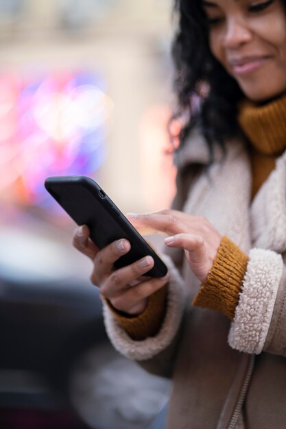 Jonge vrouw die haar telefoon buitenshuis controleert