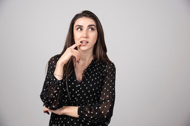 Jonge vrouw die haar vinger aan haar mond zet.