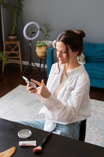 Gratis foto jonge vrouw die haar vlog bekijkt op een smartphone