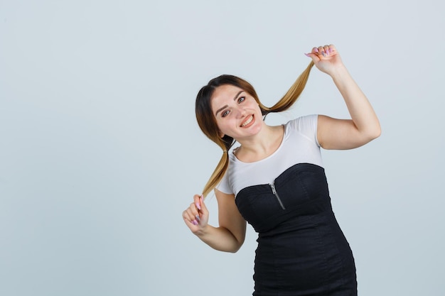 Jonge vrouw die haarlokken vasthoudt en er vrolijk uitziet