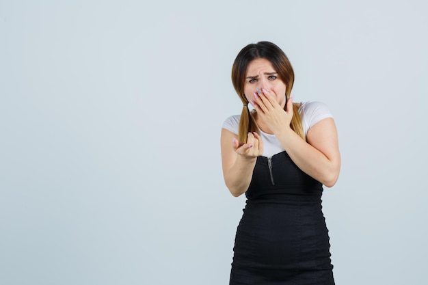 Jonge vrouw die hand op mond houdt terwijl ze naar jou wijst